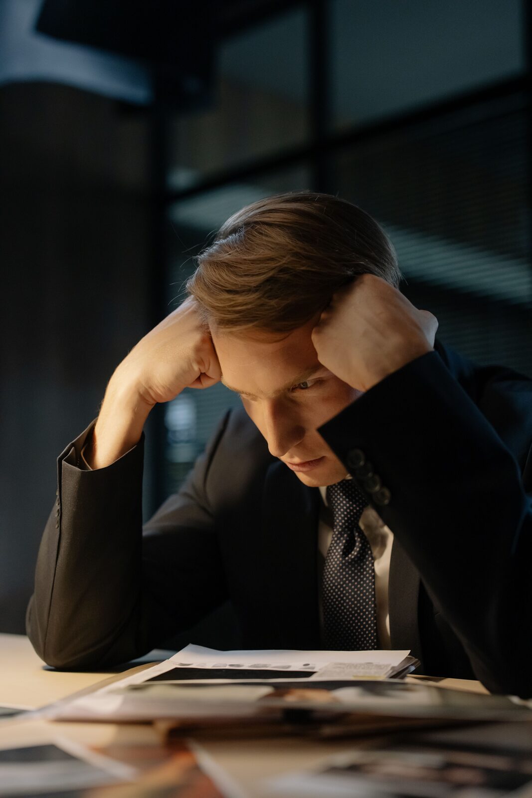 Mand med hovedet i hænderne ved skrivebordet, tegn på arbejdsstress